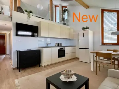 a kitchen with white cabinets and a table in a room at Klinar - Attractive new two-story apartment in Bled