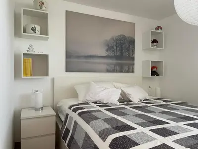 a bedroom with a bed with a black and white blanket at Klinar - Attractive new two-story apartment in Bled