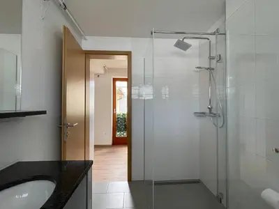 a bathroom with a glass shower and a sink at Klinar - Attractive new two-story apartment in Bled