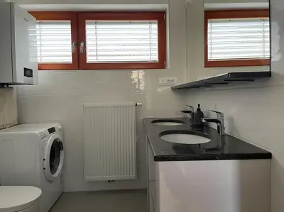 a bathroom with a sink and a washing machine at Klinar - Attractive new two-story apartment in Bled