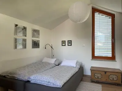 a bedroom with a bed and a table and a window at Klinar - Attractive new two-story apartment in Bled