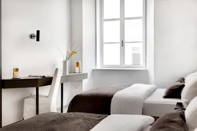a room with two beds and a desk and a window at Ljubljana Palace Suites in Ljubljana