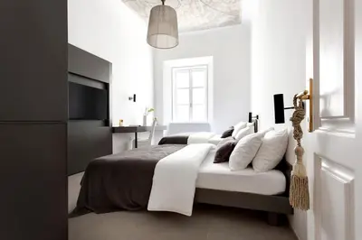 a white bedroom with a bed with white pillows at Ljubljana Palace Suites in Ljubljana