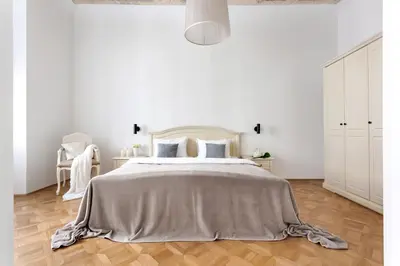 a white bedroom with a bed with a gray blanket at Ljubljana Palace Suites in Ljubljana