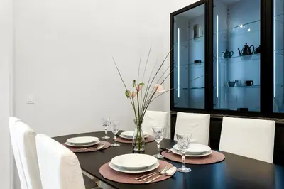 a dining room table with white chairs and a black table with glasses at Ljubljana Palace Suites in Ljubljana