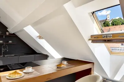an attic kitchen with a table and a window at Ljubljana Palace Suites in Ljubljana