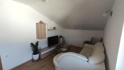 a living room with a white couch and a television at Prijetno stanovanje v bližini Term 3000 - Vivat in Moravske Toplice