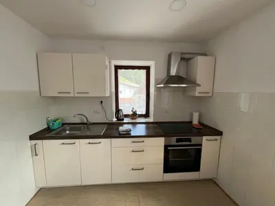 a kitchen with white cabinets and a sink and a window at Apartma Zdar in Kobarid