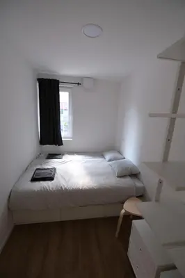 a white bedroom with a bed and a window at Apartments Emona FREE Parking & gym in Ljubljana