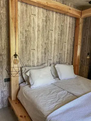 a bed in a room with a wooden wall at Koča na samem Prestiž in Šalovci