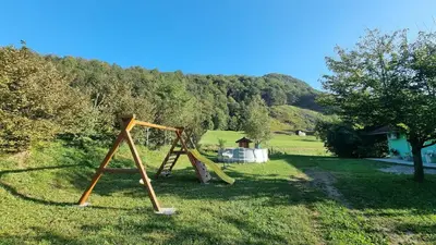 a swing set in a field with a tree at Apartma Patricija - Cozy apartments for 2 or 4 people in Tolmin