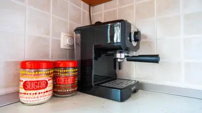 a coffee maker sitting on a counter next to two jars at Apartma Tri oljke in Dobrovo