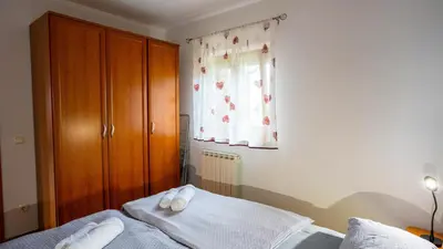 a bedroom with a bed with white sheets and a window at Apartma Tri oljke in Dobrovo