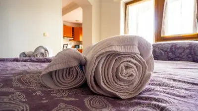 a roll of white towels on a bed at Apartma Tri oljke in Dobrovo