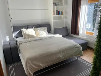 a bedroom with a bed and a couch and a window at Apartma Pohorske terase Brumen Mariborsko Pohorje in Pohorje