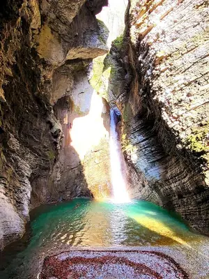 a waterfall in a canyon with a rainbow in the water at Apartma Melita in Kobarid