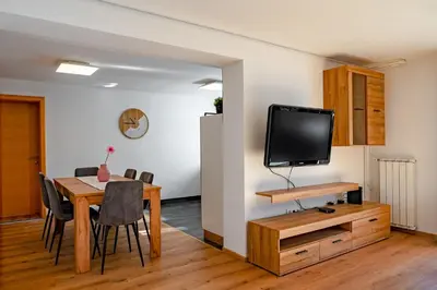 a dining room with a table and a tv on a wall at Alpski škrat, Kranjska Gora in Kranjska Gora