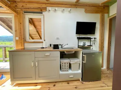 a kitchen with a counter and a tv in a room at Mini Loft close to Logar Valley in Rečica ob Savinji
