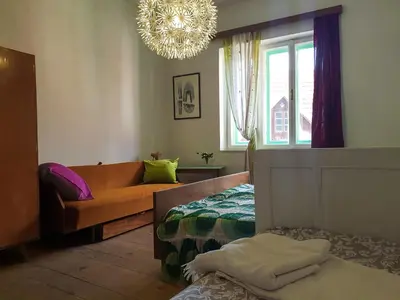 a room with a bed and a couch and a chandelier at HIŠA VELIKANKA_Giantess in Kostel
