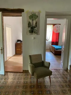 a living room with a chair and a bedroom at HIŠA VELIKANKA_Giantess in Kostel