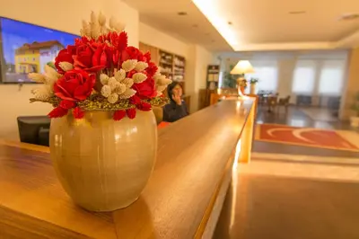 a vase with red flowers sitting on a table at B&B Bau in Maribor