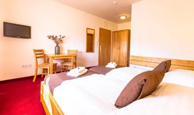 two beds in a room with a table and chairs at B&B Bau in Maribor
