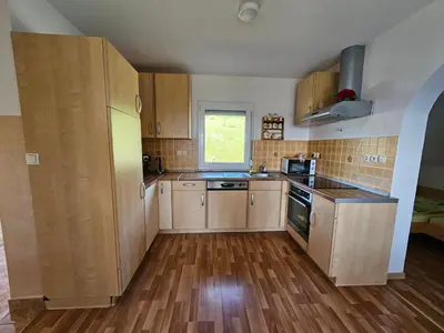 an empty kitchen with wooden cabinets and a window at zidanica Bunderšek in Šentjanž