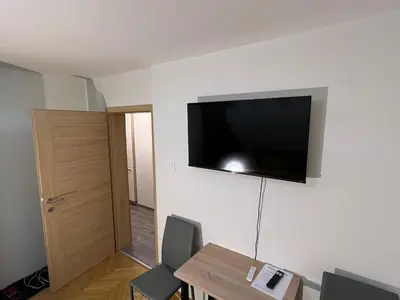 a room with a table and a television on the wall at Mici's Apartments in Visoko