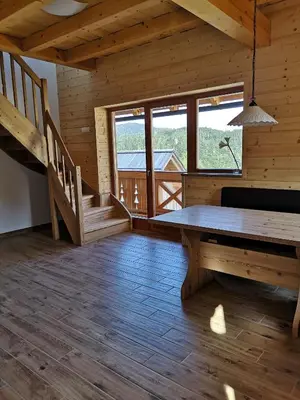 a dining room with a table and stairs in a cabin at A house with the view in Srednja Vas v Bohinju