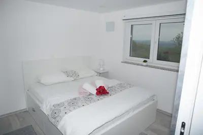 a white bedroom with a bed with a red bow on it at Apartma Lara in Lesično