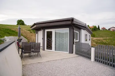 a small cottage with a fence and a table and chairs at Apartma Lara in Lesično