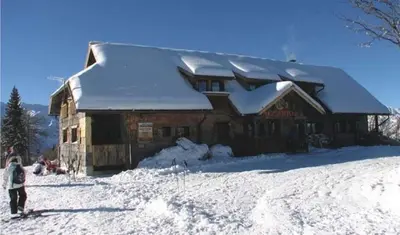 a person standing in front of a building covered in snow at Chalet Burja at Vogel mountain - cable car access or hiking - not reachable with car in Bohinj
