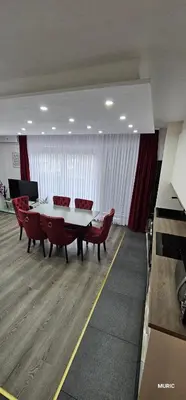 a dining room with a white table and red chairs at Apartmani MURIC Ljubljana in Ljubljana