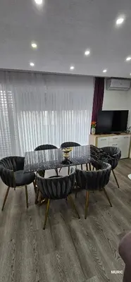a living room with a table and chairs and a television at Apartmani MURIC Ljubljana in Ljubljana