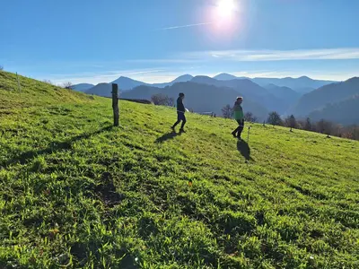 two people walking on top of a grassy hill at Miklavževa hiša with a bread oven in Železniki