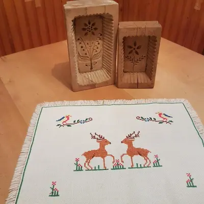 a table with two wooden boxes and a rug with deer on it at Miklavževa hiša with a bread oven in Železniki