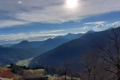 a view of a mountain range with the sun in the sky at Miklavževa hiša with a bread oven in Železniki