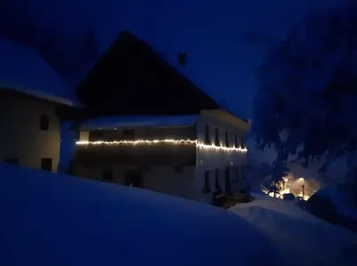 a building with lights on the side of it at night at Miklavževa hiša with a bread oven in Železniki
