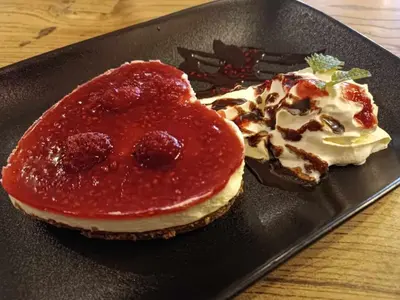 a black plate with a sandwich with strawberry jam and a dessert at Landena Apartments Lendava in Lendava