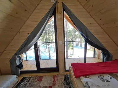 a bedroom with large windows in a log cabin at HIŠA ZIMAZAKON BLOKE in Nova Vas