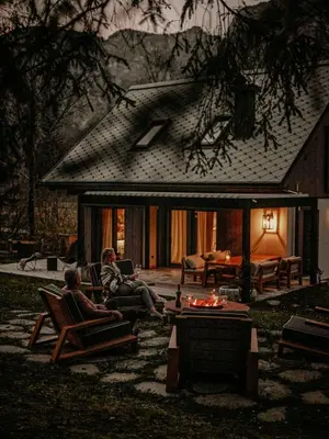 two people sitting in chairs in front of a house at Fox on the Rocks Chalet in Bohinj