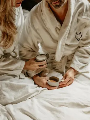 a man and woman sitting in bed holding cups of coffee at Fox on the Rocks Chalet in Bohinj