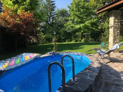 a swimming pool in a yard next to a chair at Family lake house Zbilje in Ljubljana