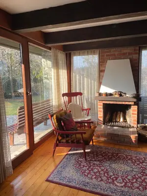 a living room with a fireplace and a rocking chair and a chair at Family lake house Zbilje in Ljubljana