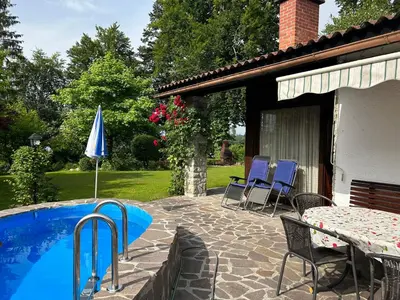 a patio with a table and chairs and a pool at Family lake house Zbilje in Ljubljana