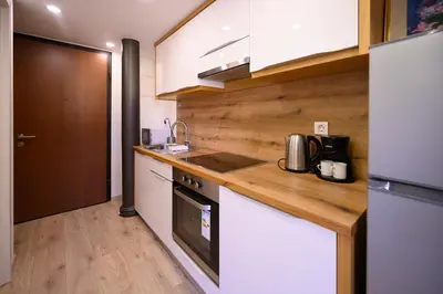 a kitchen with white cabinets and a wooden counter top at The Modern Loft in Ljubljana