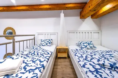 two beds in a room with white walls and wooden ceilings at The Modern Loft in Ljubljana