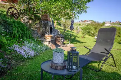 a chair and a table with a candle and a bottle at Vineyard Cottage Klemencic in Novo Mesto