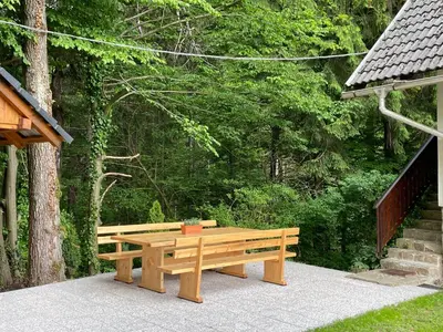 a wooden bench sitting on a sidewalk next to a forest at Vintage Holiday House in Šoštanj