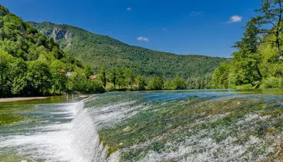 a waterfall in the middle of a river at Madronič family estate - Kolpa river in Stari Trg ob Kolpi